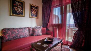 A living room with a red sofa, a wooden coffee table, and two framed floral paintings on the wall.