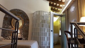 Une pièce avec un mur en pierre, une cloison en verre et un plafond en bois.