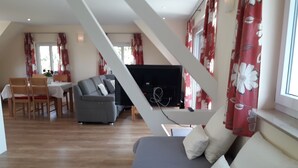 Un salon moderne avec un canapé, un téléviseur et un coin repas.