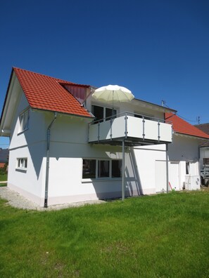 A two-story house with a red-tiled roof, a balcony with a white umbrella, and a small window. - Buche (Ueberlingen)