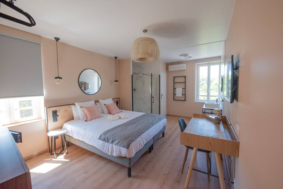 A modern bedroom with a bed, bedside table, and a desk with chairs.