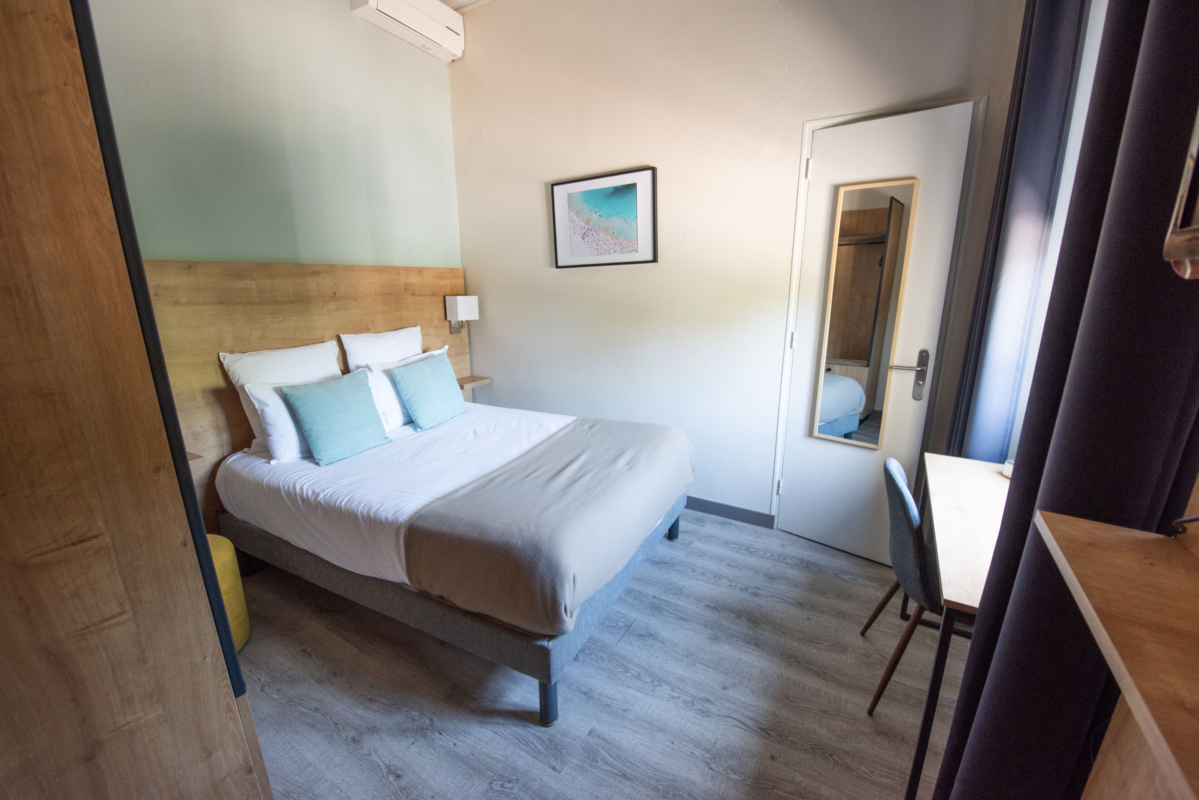 A bedroom with a bed, bedside table, and a mirror.