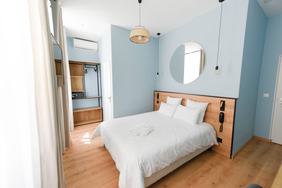 A bedroom with a wooden bed, a round mirror, and a wardrobe.