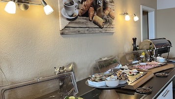 A buffet setup with various food items, a coffee station, and a decorative wall piece.