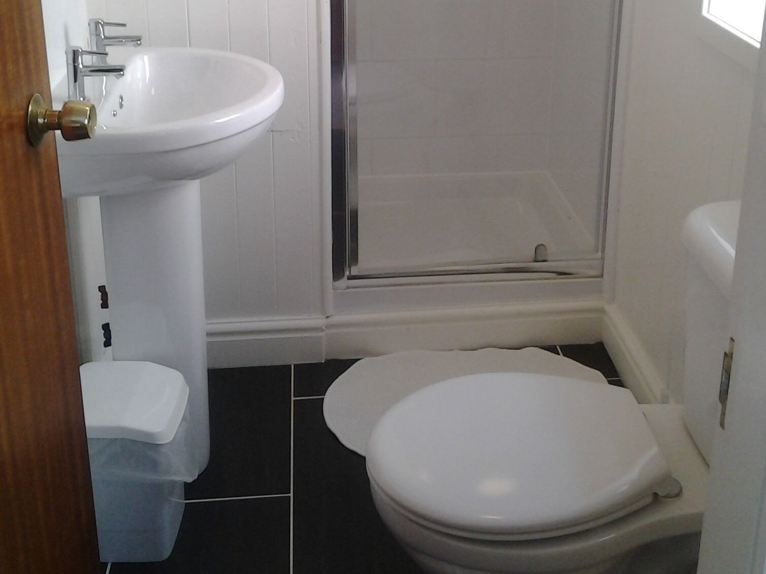 Un baño con lavamanos, inodoro y ducha blancos.