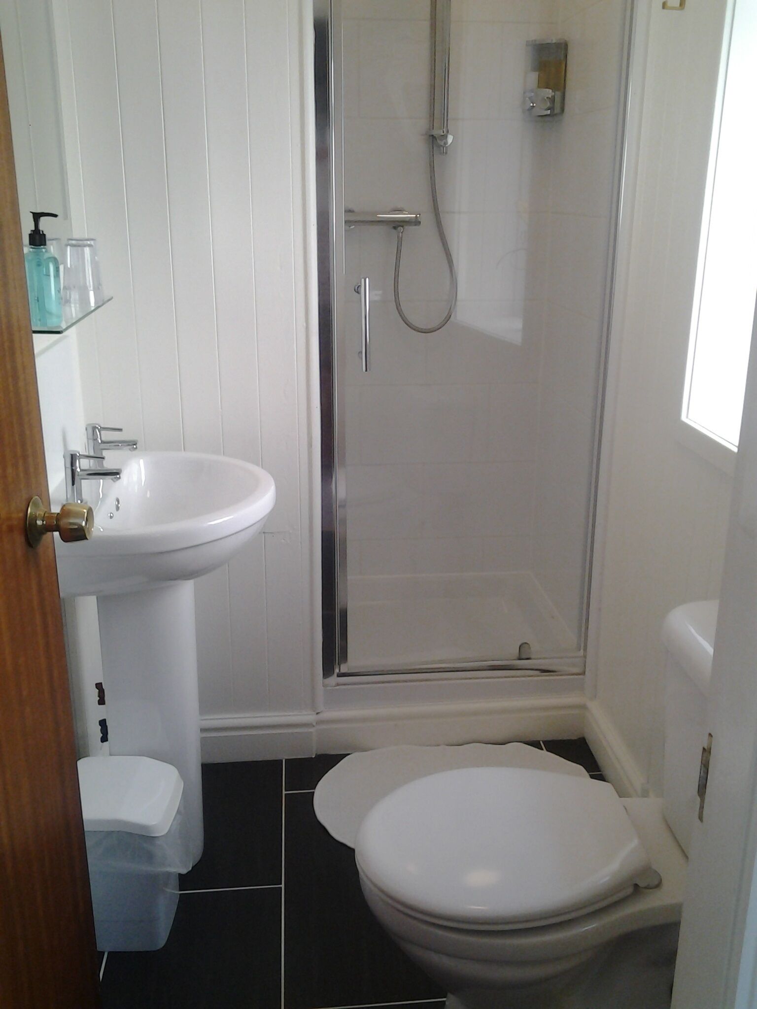 A bathroom with a white sink, toilet, and glass-enclosed shower.
