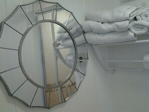 A bathroom with a round mirror and a towel rack. - Le Maitre (Southport)
