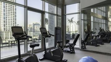 A gym with exercise equipment, large windows, and a view of buildings.