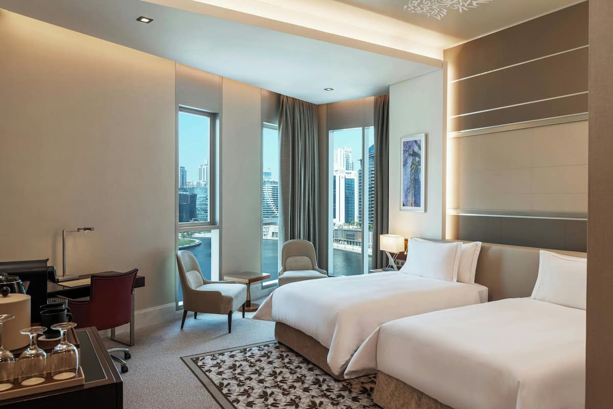 Ein Hotelzimmer mit einem großen Bett, einem Schreibtisch, einem Stuhl und Blick auf die Stadt.