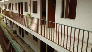 A corridor with multiple rooms, each with a door and window, and a balcony with a metal railing. - Hotel El 2000 (Morelia)