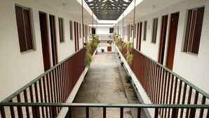 A corridor with a central walkway, flanked by railings and potted plants. - Hotel El 2000 (Morelia)
