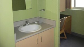 Un baño pequeño de un solo ambiente con lavamanos, espejo y armario.