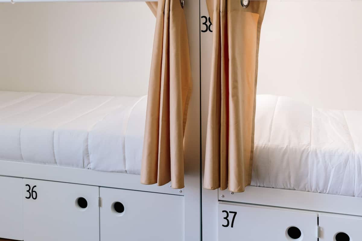 A bunk bed room with curtains, white bedding, and numbered storage compartments.
