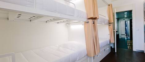 A bunk bed room with a white mattress, beige curtains, and a wooden floor.