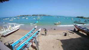 Una playa con varias embarcaciones amarradas y algunas personas en la arena.