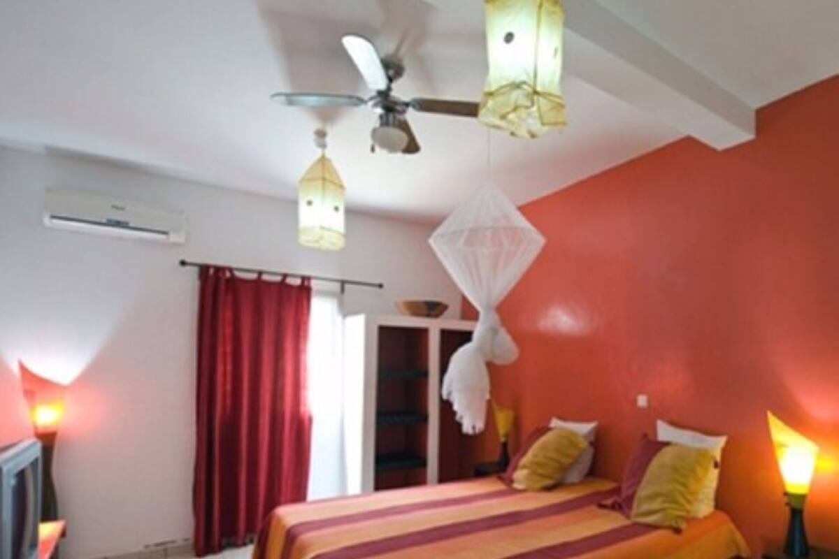 A room with a bed, a ceiling fan, and a window with red curtains.
