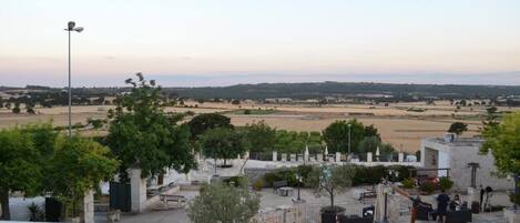 Una terraza con vistas a un paisaje rural, mobiliario exterior y una farola.