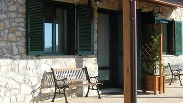 A stone building with a porch, green shutters, and outdoor seating.