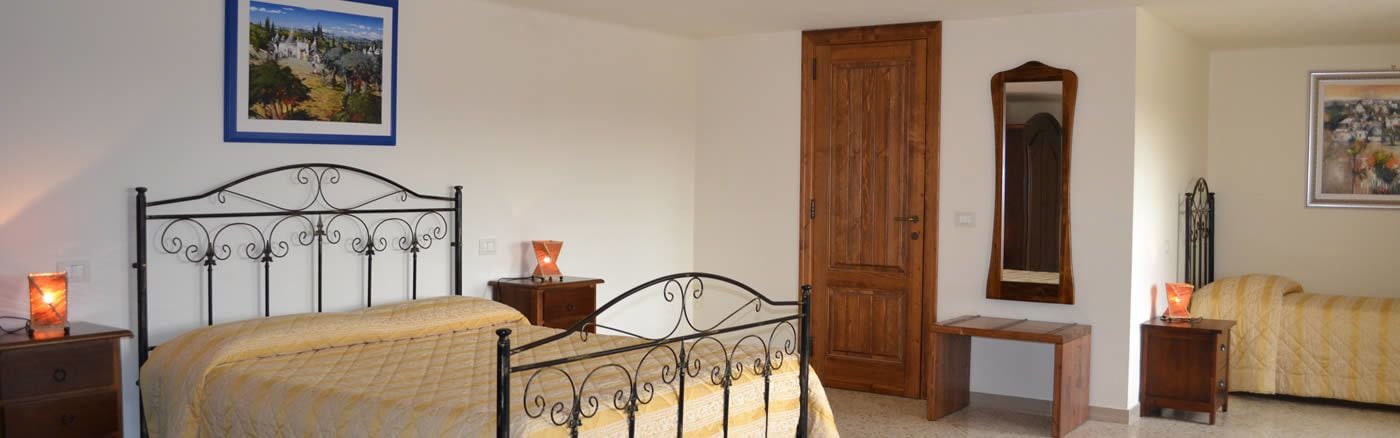 A bedroom with a bed, bedside tables, a wooden door, a mirror, and a framed picture on the wall.