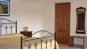 A bedroom with a bed, bedside tables, a wooden door, a mirror, and a framed picture on the wall.