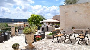 Une terrasse extérieure avec un sol en pierre, des sièges et une vue sur le paysage.