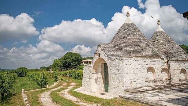 Un bâtiment en pierre avec une porte verte et un chemin de pierre menant à l’entrée.