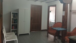 Une pièce avec une porte en bois, une armoire blanche, un sol à motifs et une petite table accompagnée de deux chaises.