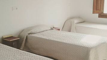 A room with two beds, a small bedside table, and a wall-mounted radiator.