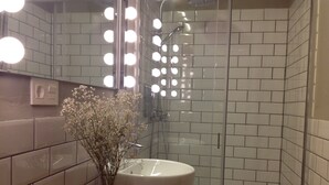 Une salle de bain avec un lavabo blanc, un meuble-lavabo en bois et un miroir avec éclairage intégré.