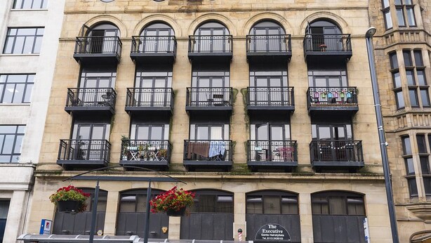 A building with multiple balconies, each with a black railing and potted plants. - Victoria House Apartments (Leeds)