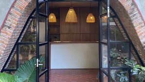 A modern entrance with a brick archway, glass doors, and hanging pendant lights. - Roca Azul (Jocotepec)