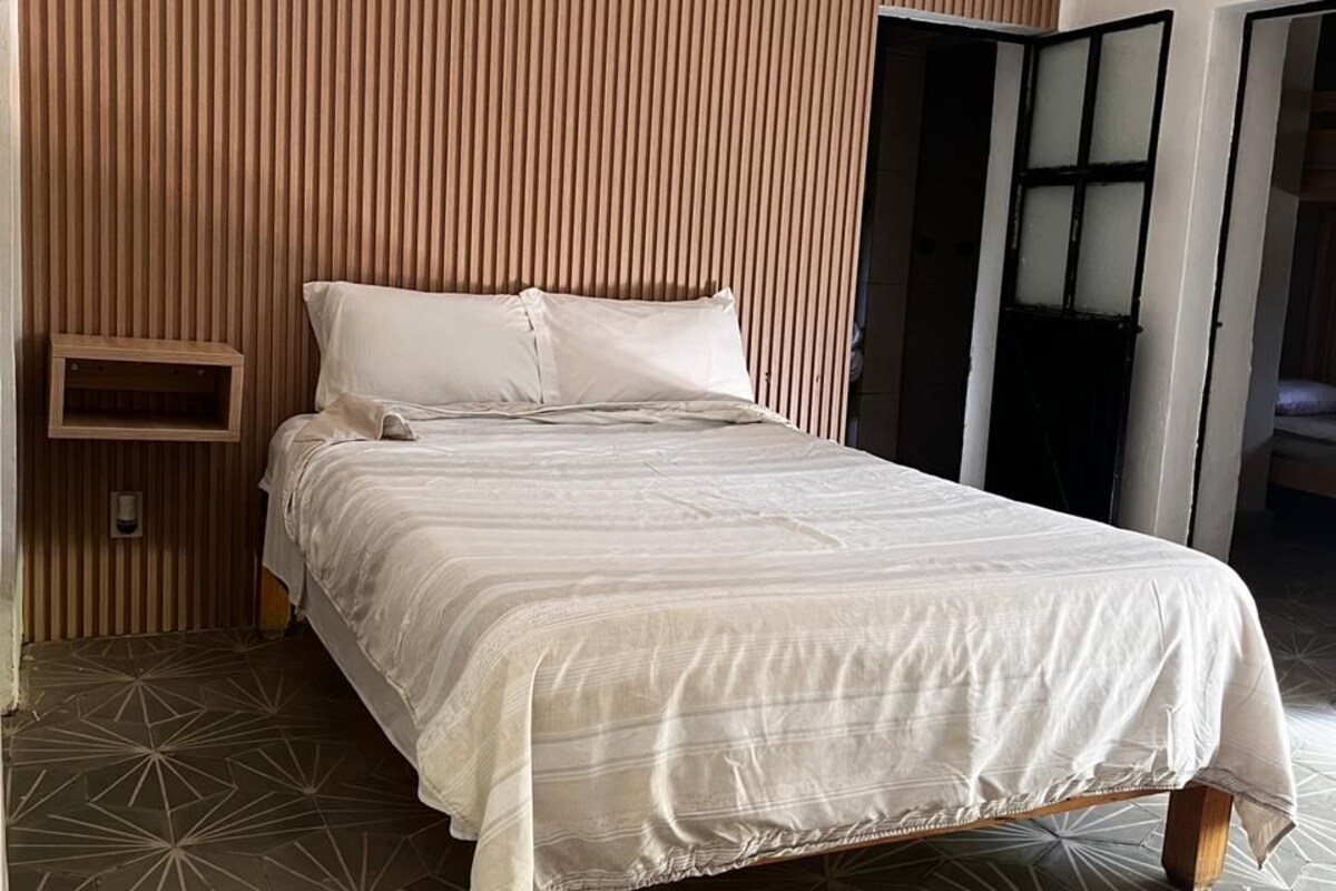 A bedroom with a bed, a wooden slat wall, and a geometric patterned floor.