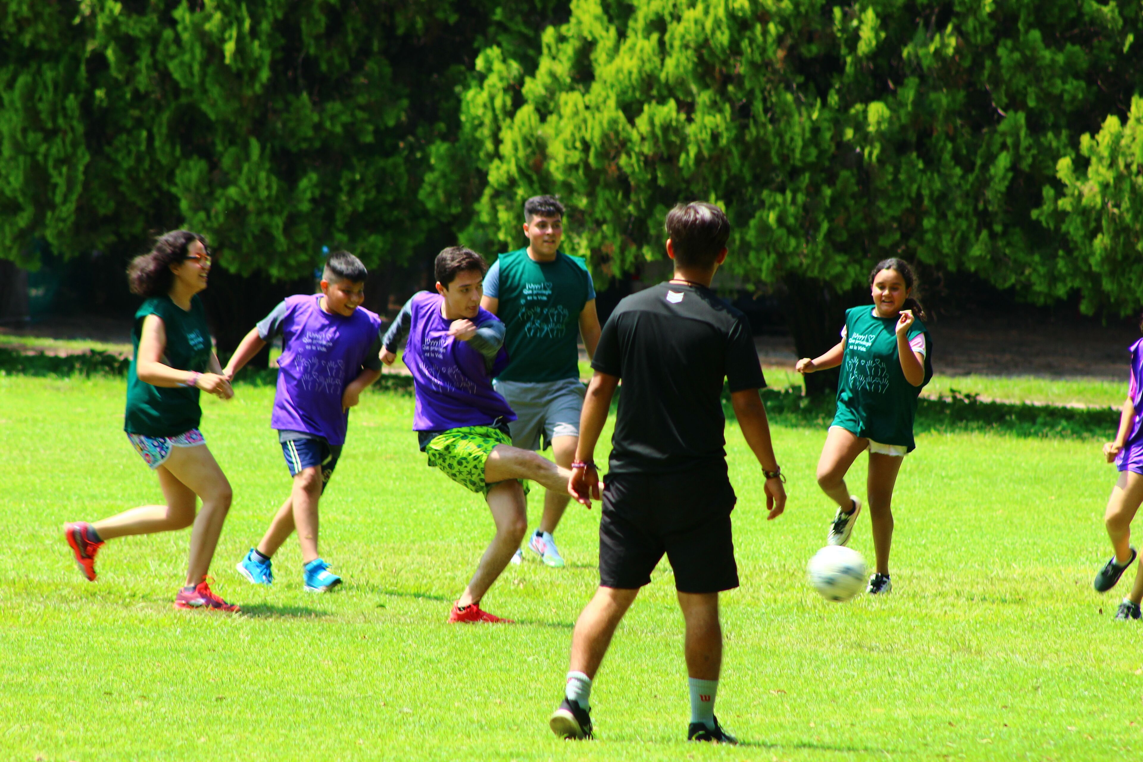 A group of people playing soccer on a grassy field.