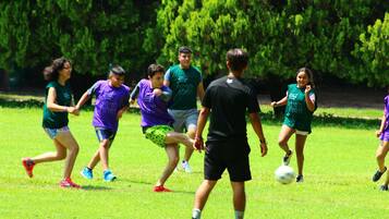 A group of people playing soccer on a grassy field.