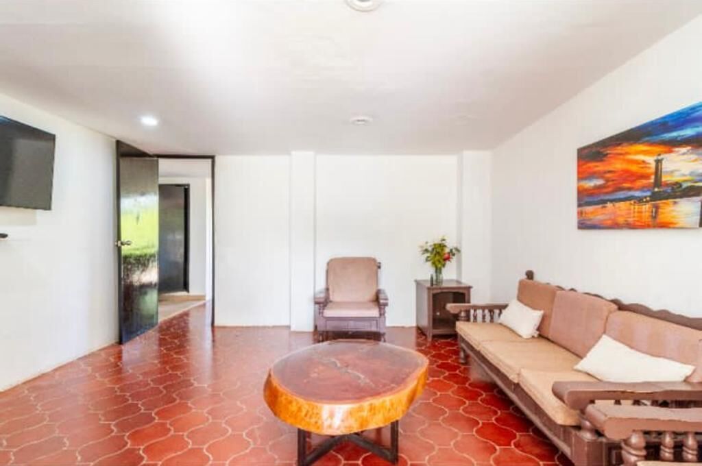 Una habitación con sofá, una mesa redonda de madera, una silla y un cuadro en la pared.