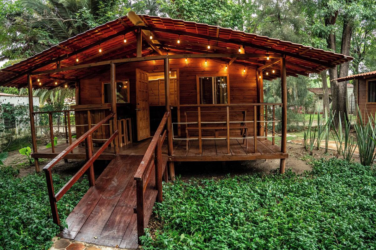 A wooden cabin with a porch and a staircase leading to the entrance.