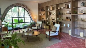 A modern interior with a large arched window, wooden shelving with decorative items, and comfortable seating. - Roca Azul (Jocotepec)