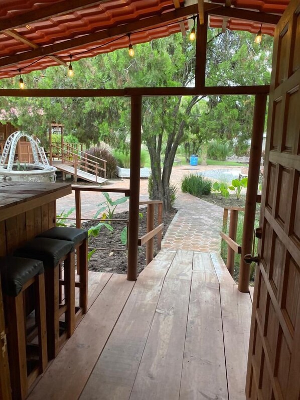 A wooden deck with a covered area, a small bridge, and a pool in the background. - Roca Azul (Jocotepec)