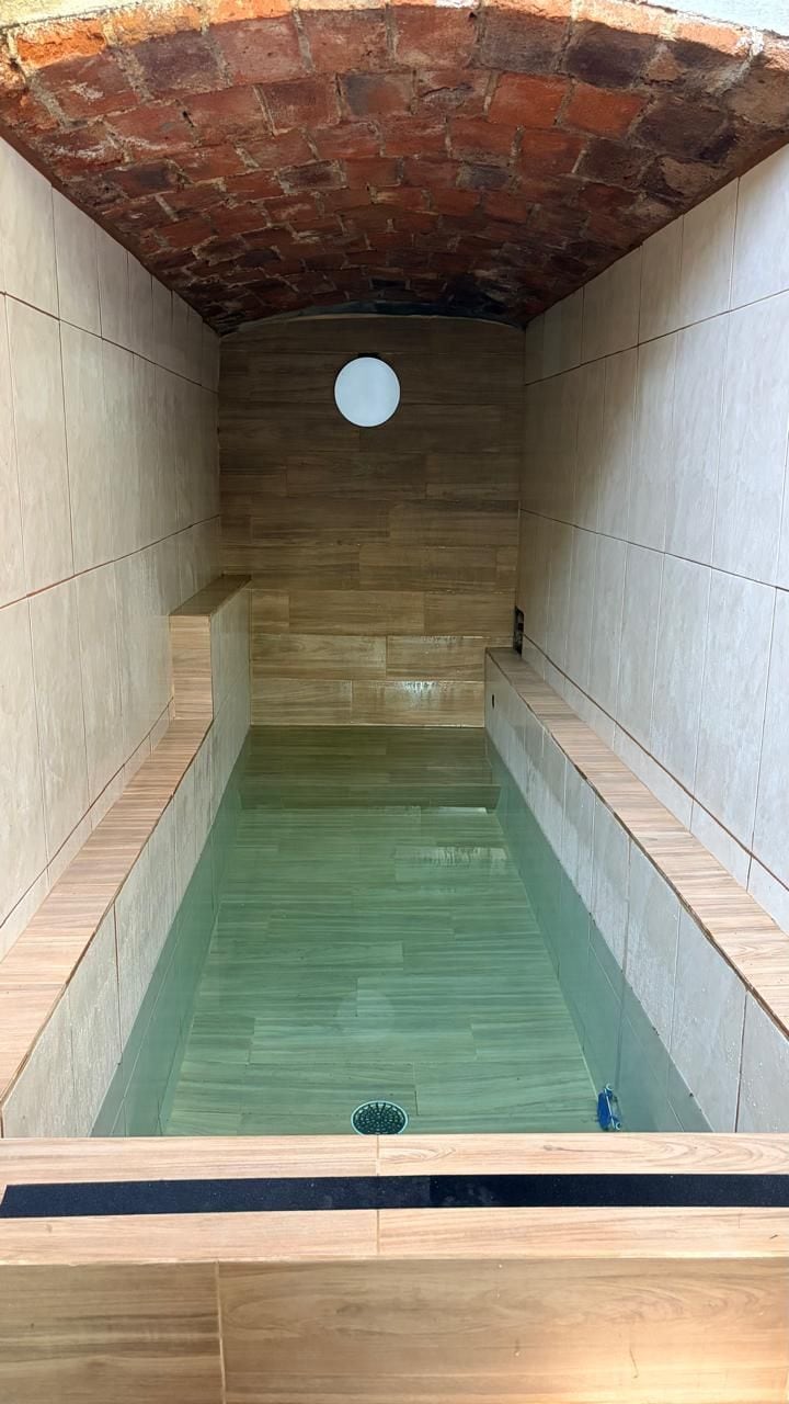 Un cuarto de spa con techo de ladrillo, paredes de azulejos y una piscina rectangular.