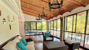 A spacious room with wicker furniture, large windows, and a brick ceiling. - Roca Azul (Jocotepec)