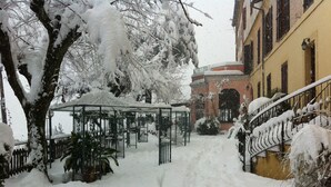 A snow-covered courtyard with a gazebo, a staircase, and a building with a yellow facade. - Bed & Breakfast Ristorante Belvedere (Subiaco)