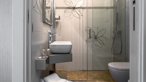 Un baño moderno con lavamanos, espejo y inodoro blancos.