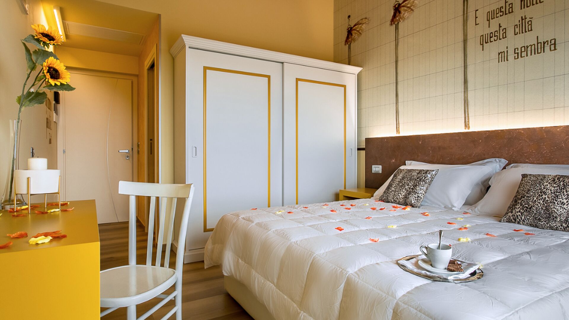 Una habitación de hotel con cama, sillón, escritorio y armario.