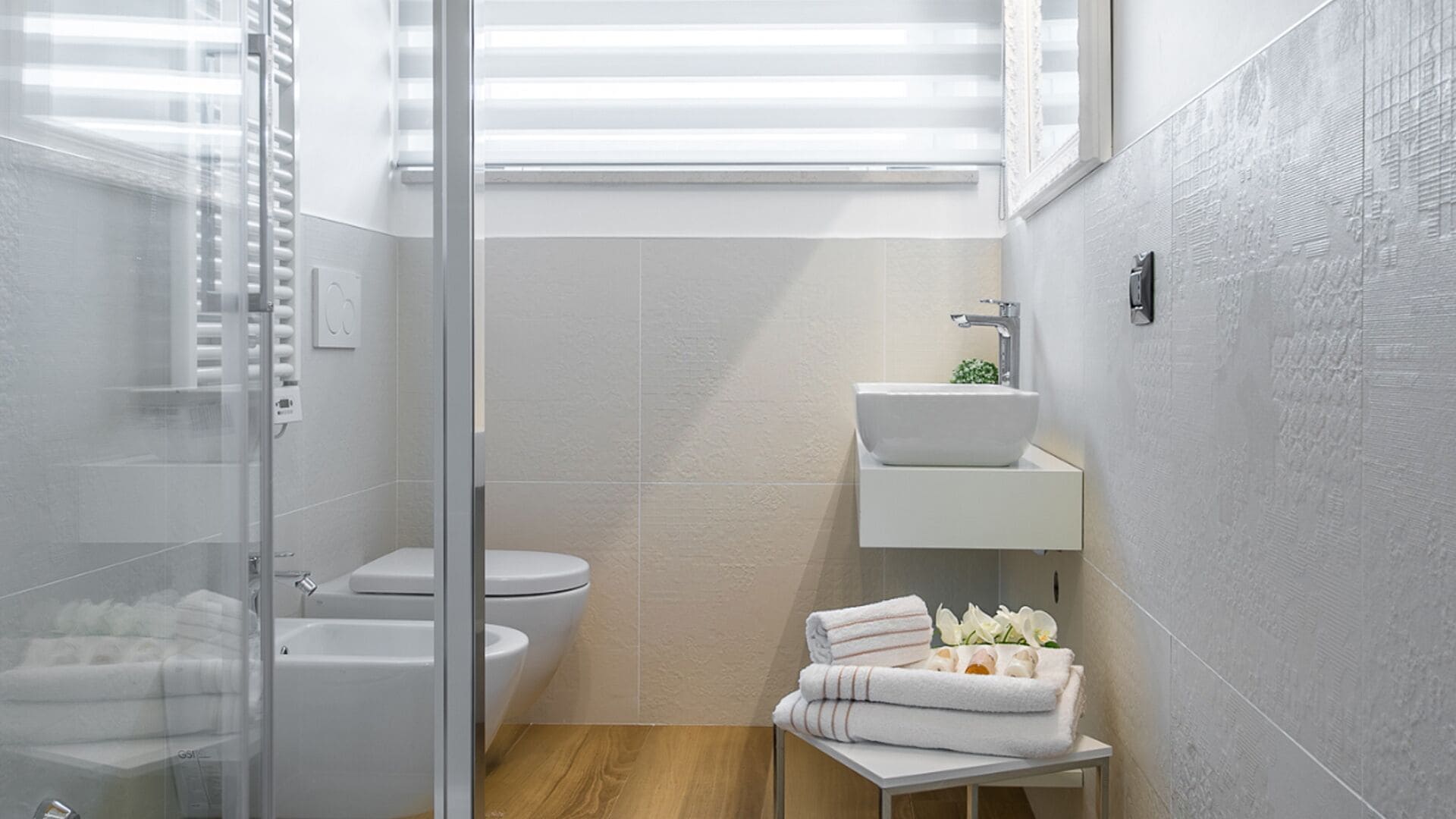 A modern bathroom with a glass shower enclosure, a white sink, and a toilet.