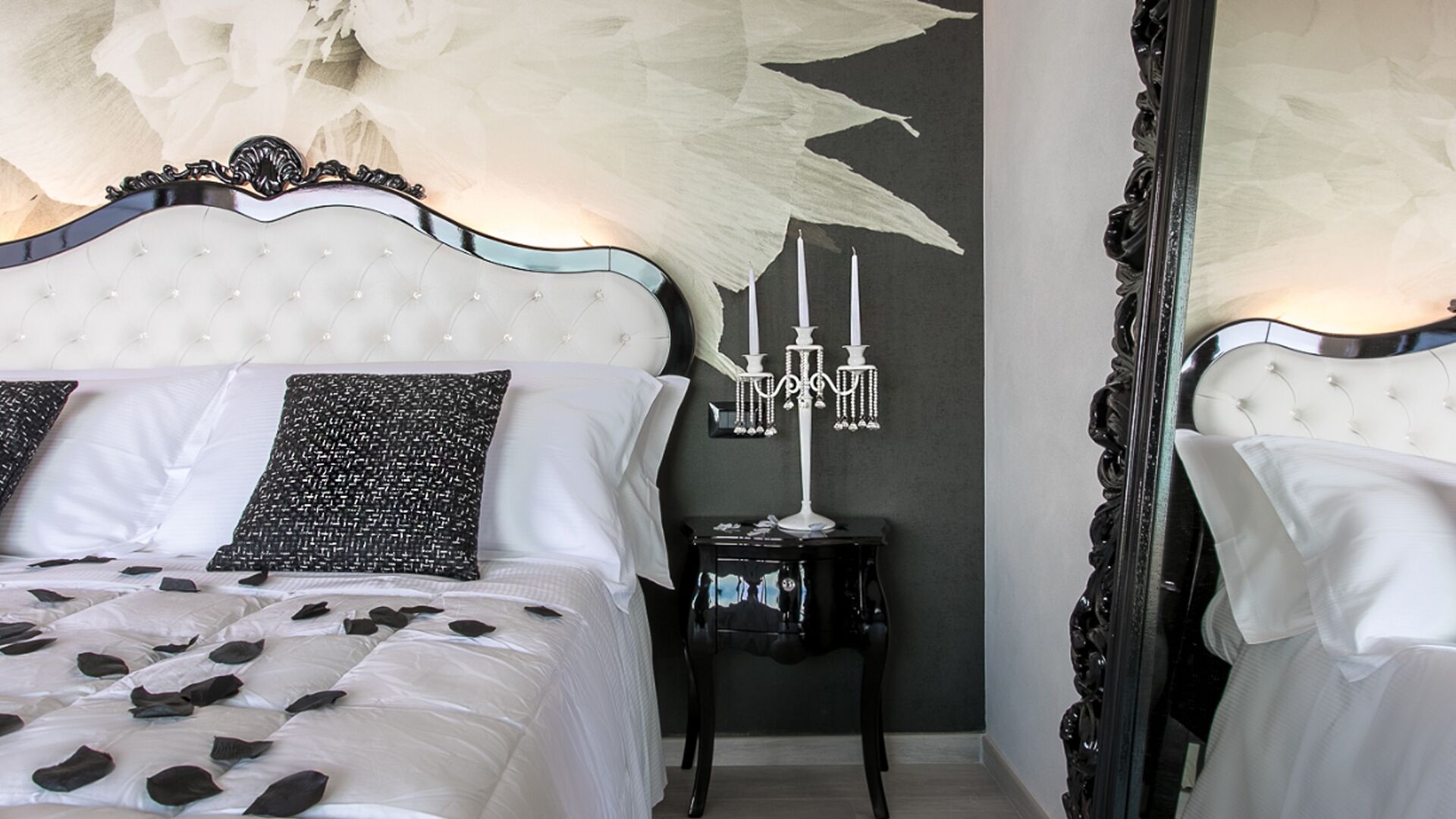 A bedroom with a large bed, a chandelier, and a mirror.