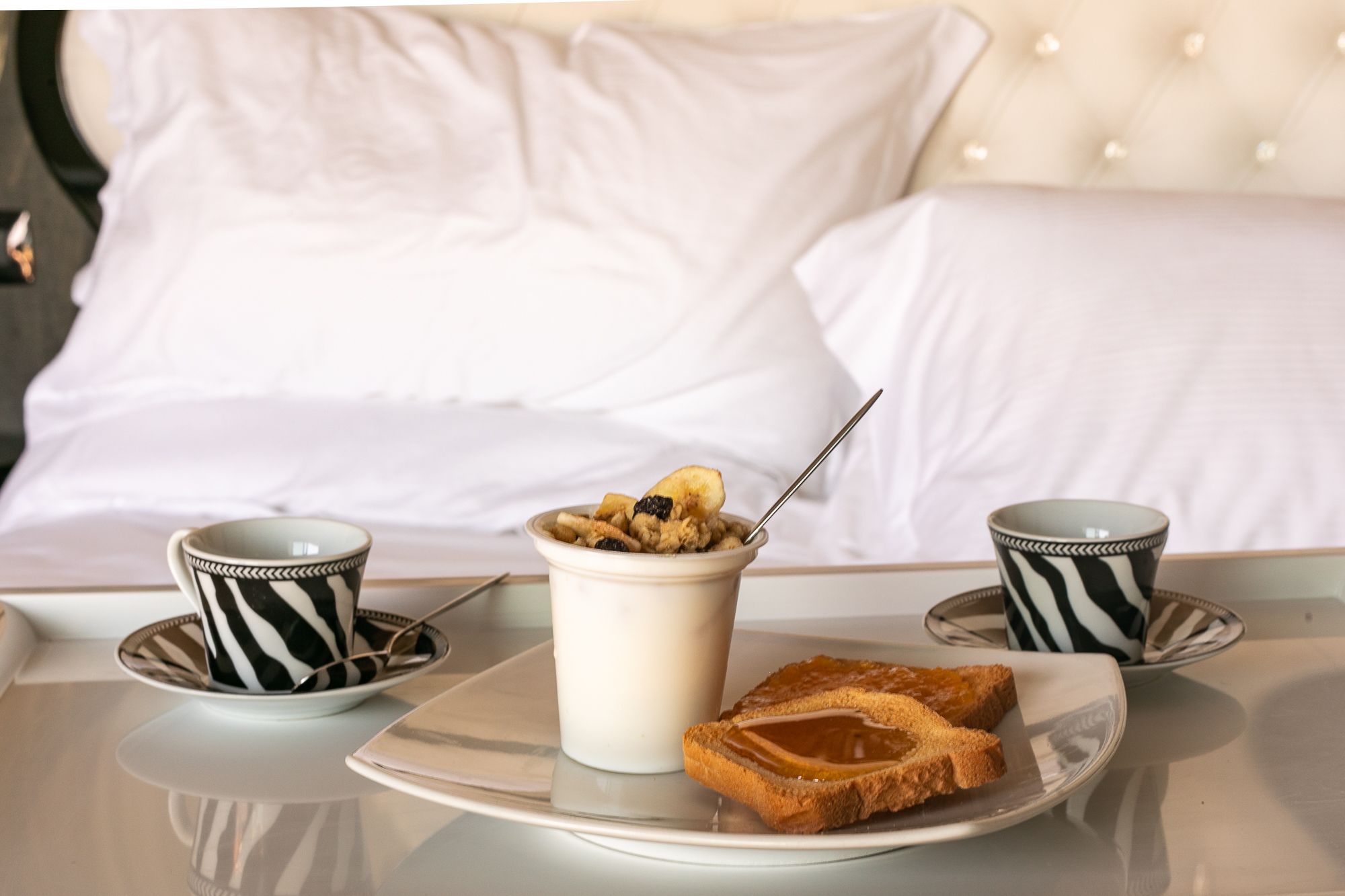 A breakfast setup with a bowl of cereal, two cups, and toast on a tray.