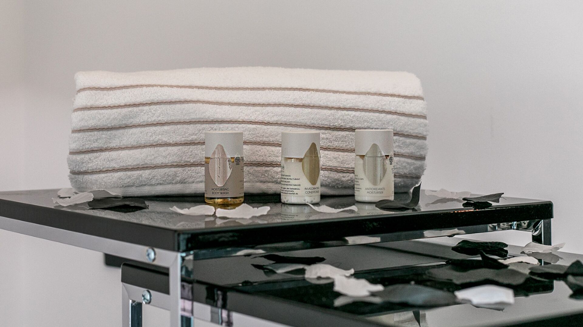 A bathroom counter with three skincare products and a striped towel.