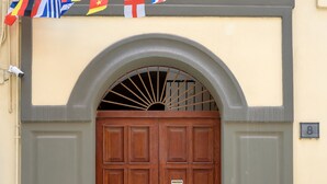 A double wooden door with a small sign, a number plate, and a flag decoration above it. - Caruso Suite (Sorrento)