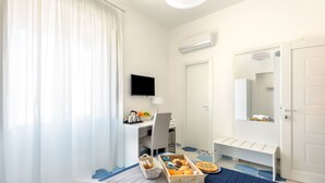 A hotel room with a bed, a desk, a chair, a TV, and a bathroom. - Caruso Suite (Sorrento)