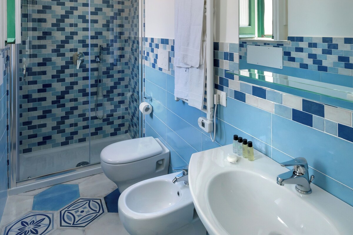 Une salle de bain avec une douche, deux toilettes, un lavabo et un miroir.